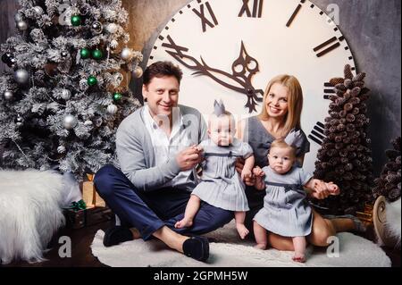 Une grande famille heureuse avec des enfants jumeaux dans l'intérieur de la maison du nouvel an sur fond d'une grande horloge. Banque D'Images