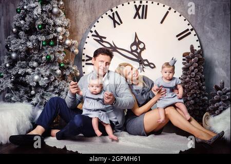 Une grande famille heureuse avec des enfants jumeaux dans l'intérieur de la maison du nouvel an sur fond d'une grande horloge. Banque D'Images