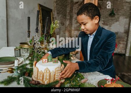 Garçon tenant un gâteau de Noël décoré de pain d'épice maison fait main. Idée pour les friandises faites à la main Happy Year festive. Banque D'Images