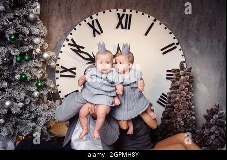 Une grande famille heureuse avec des enfants jumeaux dans l'intérieur de la maison du nouvel an sur fond d'une grande horloge. Banque D'Images