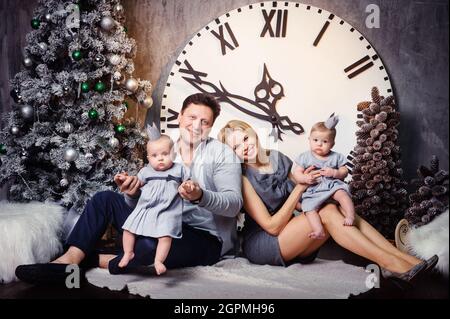 Une grande famille heureuse avec des enfants jumeaux dans l'intérieur de la maison du nouvel an sur fond d'une grande horloge. Banque D'Images