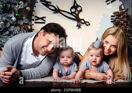 Une grande famille heureuse avec des enfants jumeaux dans l'intérieur de la maison du nouvel an sur fond d'une grande horloge. Banque D'Images