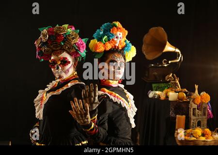 Personnes vêtues de costumes noirs folkloriques mexicains et très colorés, avec des ornements faisant référence au jour des morts, maquillage de crâne Banque D'Images