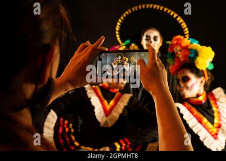 Personnes vêtues de costumes noirs folkloriques mexicains et très colorés, avec des ornements faisant référence au jour des morts, maquillage de crâne Banque D'Images