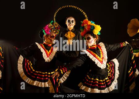 Personnes vêtues de costumes noirs folkloriques mexicains et très colorés, avec des ornements faisant référence au jour des morts, maquillage de crâne Banque D'Images