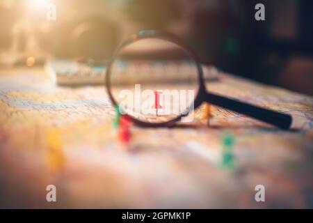 Une loupe avec des broches épinglées sur la carte. Punaise montrant l'emplacement d'un point de destination sur une carte. Concept de plan de voyage. Banque D'Images