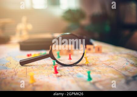 Une loupe avec des broches épinglées sur la carte. Punaise montrant l'emplacement d'un point de destination sur une carte. Concept de plan de voyage. Banque D'Images