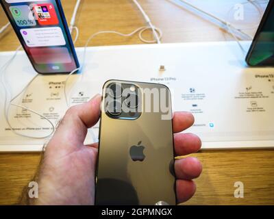 Main masculine regardant la vue arrière de l'ensemble de caméras triple amélioré sur l'iPhone 13 Pro Banque D'Images