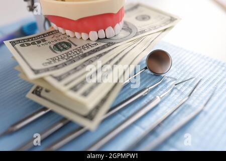 Instrument de mâchoire artificielle dentaire et billets de cent dollars sur le bureau de dentiste Banque D'Images