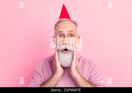 Photo de l'homme impressionné joli mature habillé pull-over verres chapeau bras joues isolé couleur rose fond Banque D'Images