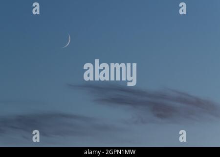 Phase de lune en croissant ciré du satellite naturel de la terre sur le ciel bleu au-dessus des nuages Banque D'Images