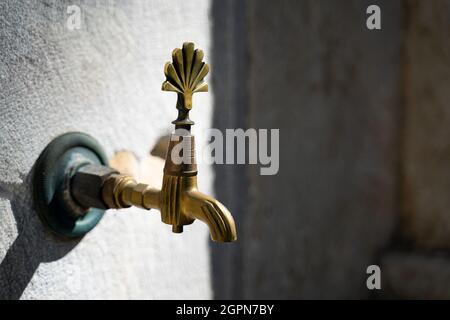 gros plan de robinet d'eau en bronze d'époque avec robinet décoré à côté d'une mosquée musulmane avec fond de pierre Banque D'Images