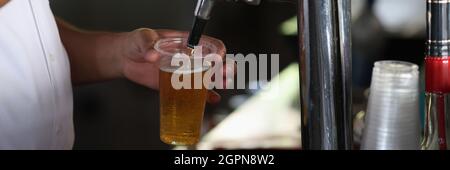 Le barman verse la bière froide de la machine dans le verre. Banque D'Images