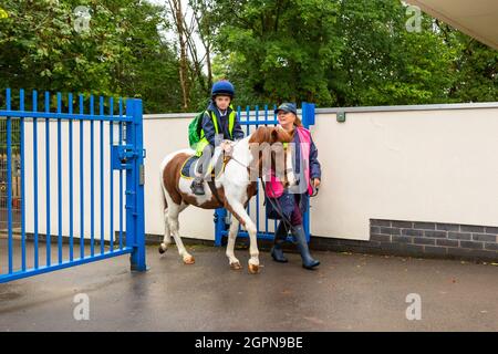 Upper Arley, Worcestershire, Royaume-Uni. 30 septembre 2021. La grand-mère Jane Mundie bat la crise de la pénurie de carburant en utilisant son poney 'Fern' à l'école. Son petit-fils Henley, âgé de 8 ans, se déplace avec assurance sur le poney à trois kilomètres de l'école primaire Upper Arley C of E dans le Worcestershire rural. « Je ne peux pas obtenir de diesel pour mon Land Rover pour le moment, mais nous n'avons pas besoin de trop nous inquiéter lorsque les enfants ont notre poney, Fern. Et c'est vraiment une façon amusante et écologique de se rendre à l'école », explique Jane. Crédit : Peter Lophan/Alay Live News Banque D'Images