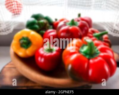 Flou. Récolte fraîche. Les poivrons texturés multicolores sont disposés sur une assiette en bois, sur le fond de la fenêtre. Poivrons doux colorés, natura Banque D'Images