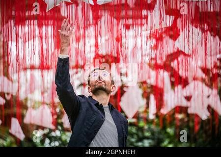 Kew Gardens, Londres, Royaume-Uni. 30 septembre 2021. Kew Staffer Paul avec l'œuvre d'art immersive à grande échelle One Thousand Springs par l'artiste japonais Chiharu Shiota, une œuvre d'art contemporaine qui pend du plafond de la Temperate House composée de 5,000 haikus suspendus dans un réseau de fils rouges. Le Japan Festival à Kew est un nouveau festival d'automne immersif célébrant les arts, les plantes et la culture du Japon avec des installations à grande échelle et de magnifiques expositions horticoles qui prennent le contrôle de la Temperate House pour le mois d'octobre. Credit: Imagetraceur/Alamy Live News Banque D'Images