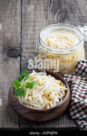 Haricots mungs marinés et germés dans un bol en bois sur une table rustique Banque D'Images