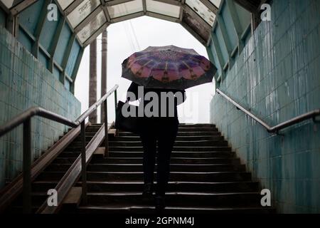 Une femme avec un parapluie va à l'extérieur. La femme monte les escaliers. Passage souterrain pour piétons. Temps pluvieux dans la ville. Banque D'Images