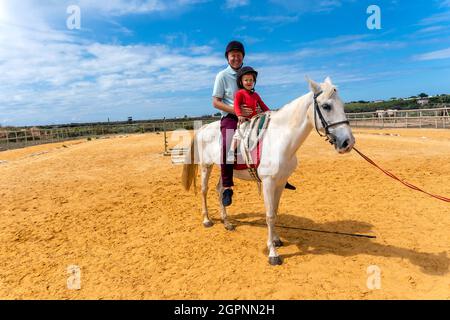 Père et fils profitant de l'équitation dans le paddock Banque D'Images