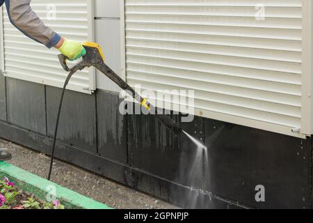 Arrosage de l'eau sur un mur sale. Désinfection du territoire. Nettoyage de la saleté sur les stores. Banque D'Images