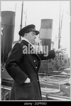 Le capitaine W. R. Crouch, maître d'écluse de Tilbury Docks, dirige les opérations dans l'écluse alors que le caisson d'entrée d'eau de refroidissement pour la raffinerie de pétrole de Coryton commence son voyage sur la Tamise. Cette image a été publiée dans l'édition d'avril 1952 du bulletin mensuel de Laing, Team Spirit. Au cours de la deuxième Guerre mondiale, John Laing & amp; son Ltd avait construit certains caissons flottants pour le port de Mulberry qui étaient utilisés pour les débarquements du jour J. Ce caisson de prise d'eau en béton de 4,200 tonnes a été construit le long des lignes du port de Mulberry et a été remorqué à 8 milles le long de la Tamise à partir de Tilbury Dock pour être installé Banque D'Images