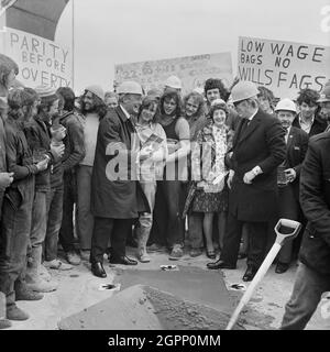 Sir Maurice Laing lors de la cérémonie de garniture sur le toit de l'immeuble de bureaux de l'usine de tabac Wills à Hartcliffe, un paquet de cigarettes Embassy vient d'être enterré symboliquement dans le dernier versement de béton. Derrière la foule, les travailleurs tiennent des pancartes protestant contre les bas salaires. Un écriteau fait référence aux salaires "Mac's Labourer", McAlpine était l'un des principaux sous-traitants du projet, tout comme Drake et Scull qui est également mentionné sur l'enseigne. Ce projet a été le premier dans lequel Laing a agi seulement dans une capacité de gestion, et non directement en employant leur main-d'œuvre, mais plutôt dans l'Usin Banque D'Images