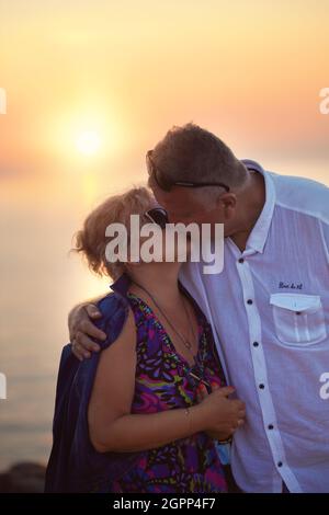 baiser tendre et romantique d'un couple âgé au coucher du soleil Banque D'Images