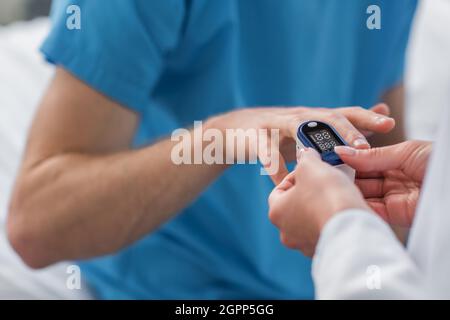 vue rognée du médecin plaçant l'oxymètre de pouls sur le doigt du patient à l'hôpital Banque D'Images