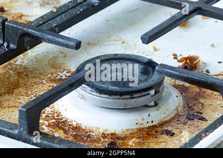 Surface du poêle à gaz sale. Brûleur à gaz moyen et grille en fonte d'un four à gaz entouré de vieux restes de nourriture et de boissons. Surface supérieure et brûlure Banque D'Images