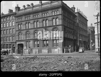 Fraser House, Charlotte Street, Manchester, 1942. Vue extérieure de Fraser House, un ancien entrepôt situé à l'angle de Charlotte Street et Portland Street, vue du sud avec des décombres en premier plan. L'entrepôt a été construit entre c1855 et 1860 par Edward Walters avec des briques rouges et des pansements en grès, et il a été utilisé comme entrepôt d'un fabricant de textiles. Il a quatre étages et un sous-sol, avec cinq baies au sud, et trois baies à l'est. Il y a un panneau sur la façade sud, lire: "AIR RAID SHELTER/ 200 PERSONNES", et au premier plan est la bombe à gravats la plus probable Banque D'Images