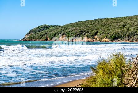 Vagues de mer dans le golfe de Baratti, Piombino, province de Livourne, Italie. Un surfeur dans la distance. Banque D'Images