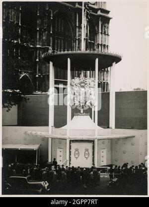 Westminster Abbey, Westminster, Greater London Authority, 3 juin-30 septembre 1953. L'entrée canopée de l'annexe construite à l'extérieur de l'entrée ouest de l'abbaye de Westminster pour le couronnement d'Elizabeth II, avec les armoiries royales et la foule faisant la queue pour entrer, vue du nord-ouest. Le couronnement d'Elizabeth II a eu lieu le 2 juin 1953. Une annexe à façade de verre, conçue par Eric Bedford, a été construite à l'extérieur de l'entrée ouest de l'abbaye de Westminster. Il devait être utilisé comme un espace pour organiser les processions avant le service de couronnement, et était connu de manière familièrement comme "l'arrivée Banque D'Images