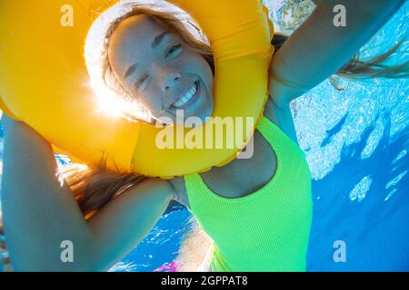 Espagne, Majorque, femme souriante nageant dans la piscine avec anneau gonflable Banque D'Images