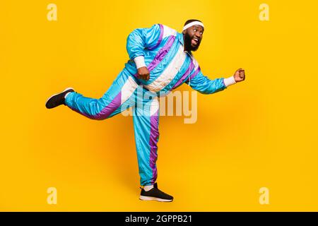 Photo de la peau douce et foncée impressionnée homme porter bleu costume bandeau danse sourire isolé couleur jaune arrière-plan Banque D'Images