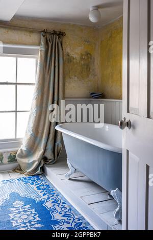 Rideaux damassés et murs en plâtre avec salle de bains sur pied dans Suffolk Cottage. Banque D'Images