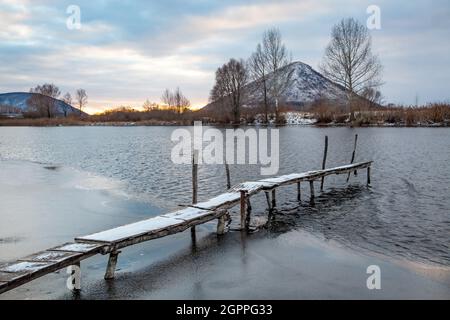 Passerelle en bois enneigée sur un étang gelé recouvert de neige Banque D'Images