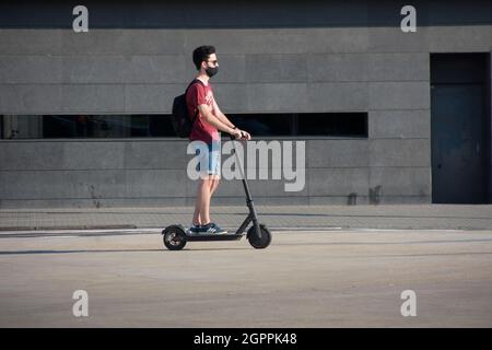 Jeune homme à cheval électrique dans une rue. Banque D'Images