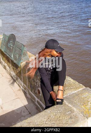 Une femme africaine heureuse profite de la chaleur du soleil posant pour des photos alors qu'elle est le long de la rivière Tay à Dundee, en Écosse Banque D'Images