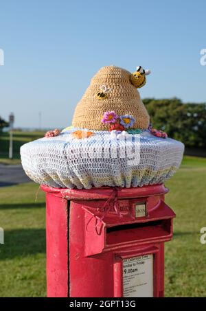 Guérilla crochet / ruche tricotée et affiche-chapeau de boîte d'abeilles sur une boîte postale dans la ville balnéaire de Southwold, Suffolk est Angleterre Banque D'Images