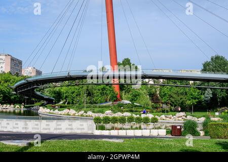 Bucarest, Roumanie - 25 mai 2021 : paysage avec le pont métallique moderne, le lac et les arbres verts dans le parc de Drumul Taberei (Parcul Drurul Taberei) également Banque D'Images