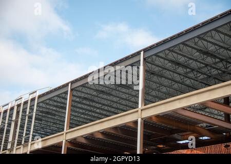 Un grand mur de bâtiment en métal de plusieurs étages avec des poutres en acier contre un ciel bleu.La structure industrielle est le coin d'un gratte-ciel Banque D'Images