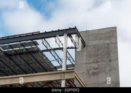 Un grand mur de bâtiment en métal de plusieurs étages avec des poutres en acier contre un ciel bleu.La structure industrielle dans le coin d'un bâtiment gratte-ciel avec Banque D'Images