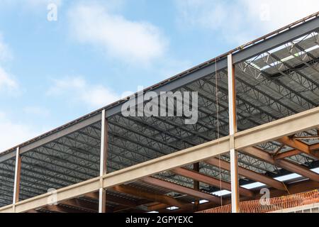 Un grand mur de bâtiment en métal de plusieurs étages avec des poutres en acier contre un ciel bleu.La structure industrielle est le coin d'un gratte-ciel Banque D'Images