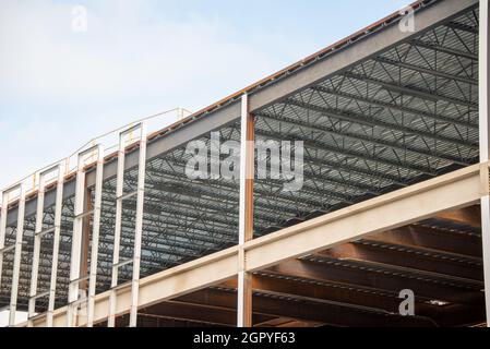 Un grand mur de bâtiment en métal de plusieurs étages avec des poutres en acier contre un ciel bleu.La structure industrielle est le coin d'un gratte-ciel Banque D'Images