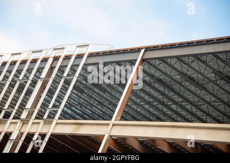 Un grand mur de bâtiment en métal de plusieurs étages avec des poutres en acier contre un ciel bleu.La structure industrielle est le coin d'un gratte-ciel Banque D'Images