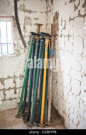 Des accessoires télescopiques sont empilés sur le mur d'une maison en construction Banque D'Images