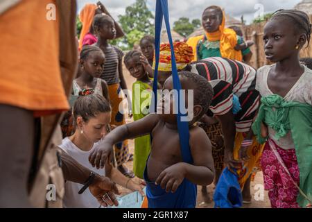 Basse, Gambie. 20 août 2021. Un agent de santé du Centre de réadaptation et d'éducation contre la malnutrition pèse un des enfants.pendant la pandémie de Covid19, les mesures de santé menées par les hôpitaux et les centres de santé ont été limitées à l'identification et au traitement des cas liés au covid-19. Maintenant que les restrictions s'assouplissent, des mesures comme le dépistage visant à cibler et à traiter les cas graves de malnutrition dans les villages ruraux de Gambie peuvent être reprises. Crédit : SOPA Images Limited/Alamy Live News Banque D'Images