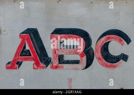 Les lettres A B C écrites sur un mur en signetant des chiffres alphabétiques et peintes sur un mur de merde. Banque D'Images