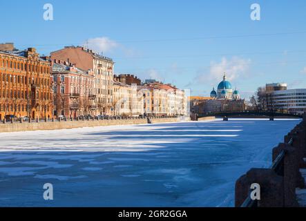 Saint-Pétersbourg ensoleillé en hiver. La rivière Fondtanka gelée, le remblai avec des bâtiments résidentiels et les dômes de la cathédrale de la Trinité Banque D'Images