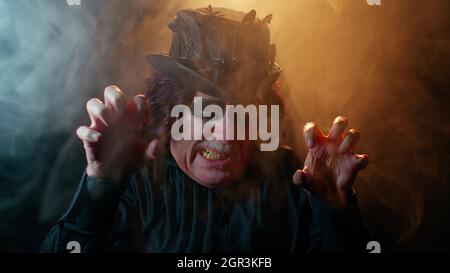Sinistre homme avec horrible effrayant Halloween sorcher maquillage en costume faisant des visages essayant de faire peur Banque D'Images
